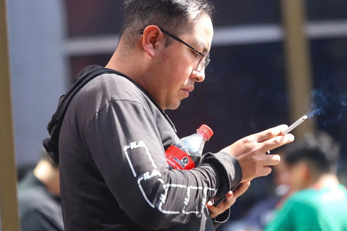 Persona consumiendo refresco y cigarro