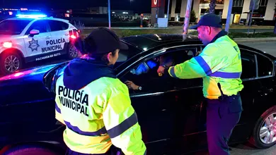Personal de seguridad realiza una prueba de alcoholímetro a un conductor.