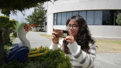 Alumna de la UAEH tomando fotografía a una escultura de una garza