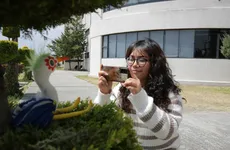 Alumna de la UAEH tomando fotografía a una escultura de una garza