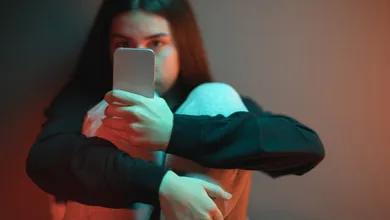 Persona utilizando un teléfono celular mientras revisa mensajes en internet.