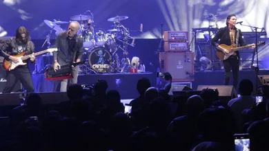 Caifanes durante una presentación en vivo con escenario iluminado.