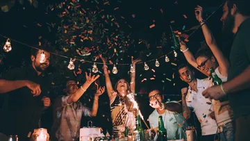 Personas celebran Año Nuevo escuchando música y brindando.