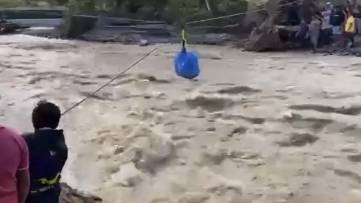 Voluntarios usan una tirolesa para cruzar víveres sobre el río desbordado en Hidalgo.