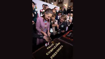 La presidenta Claudia Sheinbaum parte un pastel durante la celebración de su cumpleaños número 64 en Palacio Nacional.
