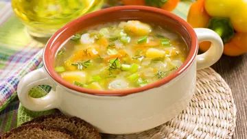 Receta tradicional de sopa de habas cocinándose en olla con cilantro y tomate.