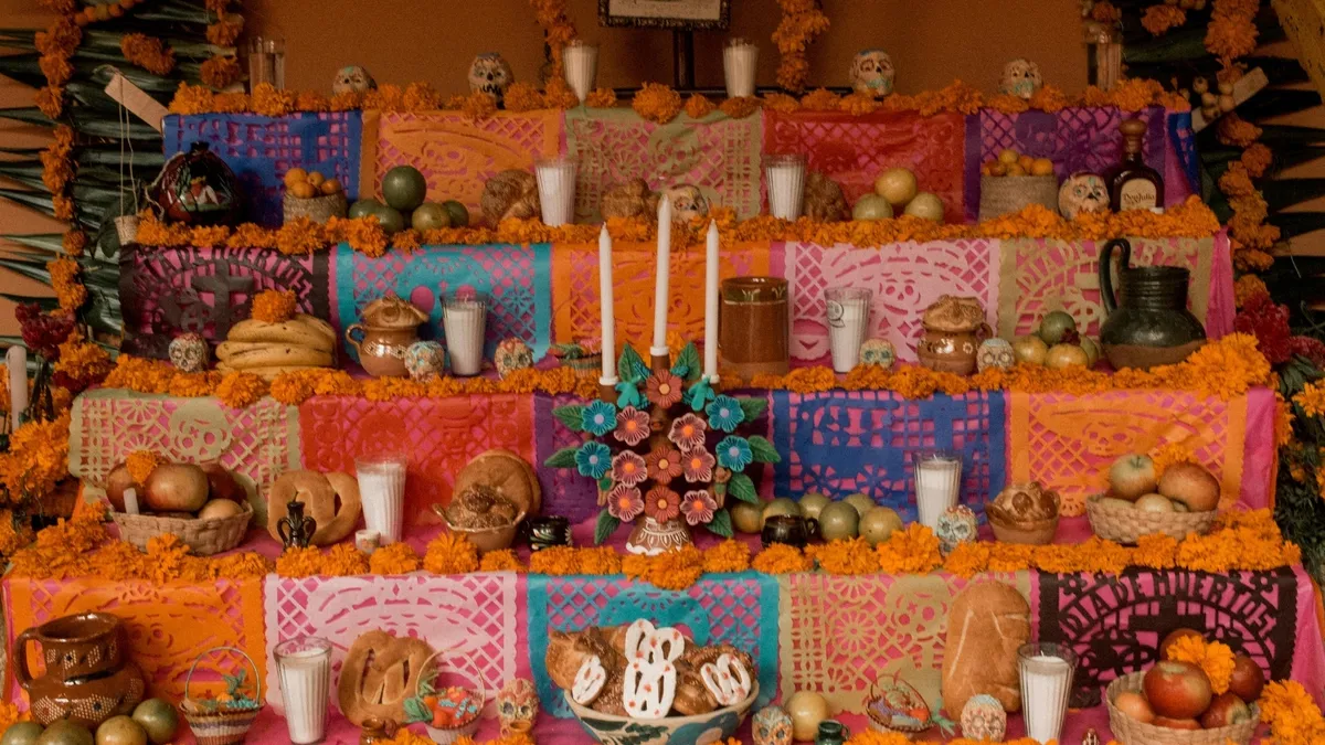 Ofrenda tradicional del Día de Muertos con flores, pan y veladoras.