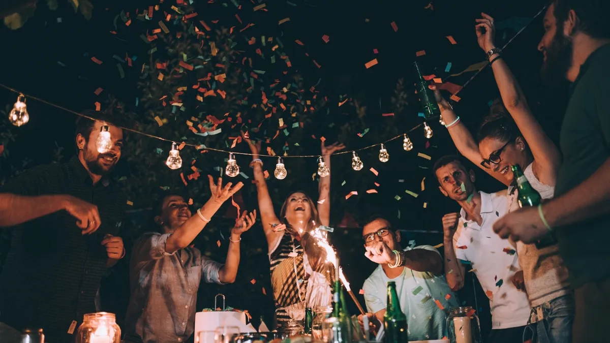 Personas celebran Año Nuevo escuchando música y brindando.